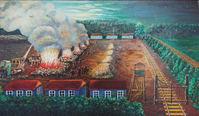 Kolorowy obraz, w centrum 5 aktywnie palących się stosów spaleniskowych, na przeciwko kopce z usypanych popiołów,  na pierwszym planie drewniane kolorowe baraki, po lewej wysoki żywopłot z drzew iglastych przed nim długie tory kolejowe. 