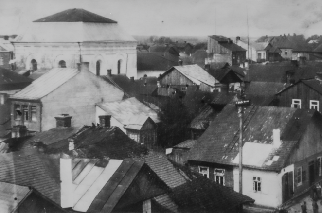 Panorama dawnej dzielnicy żydowskiej w Tomaszowie Lubelskim z gęstą zabudową niskich domów i dużą synagogą w tle.