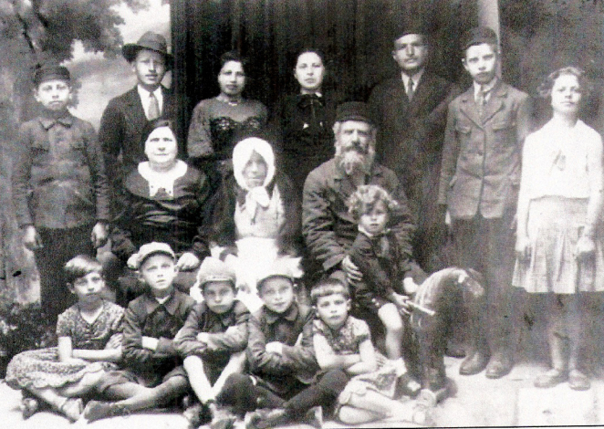 Czarno-biała fotografia grupowa rodziny Honorowów i Balsenbaumów z Tomaszowa Lubelskiego — kilka pokoleń kobiet, mężczyzn i dzieci pozujących razem na tle studia fotograficznego.