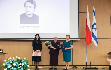 Kolorowa fotografia z 2017 roku przedstawiająca Danutę Wasyl i Krystynę Ważną-Wujec stojące na scenie w Lublinie podczas uroczystości wręczenia odznaczenia Sprawiedliwy wśród Narodów Świata, z portretem Elżbiety Ważnej wyświetlonym w tle.