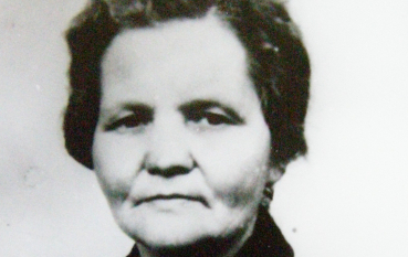 Czarno-białe zdjęcie portretowe Julii Pępiak, ujęcie od ramion w górę, w ciemnym stroju z jasnym kołnierzem, na jasnym tle.