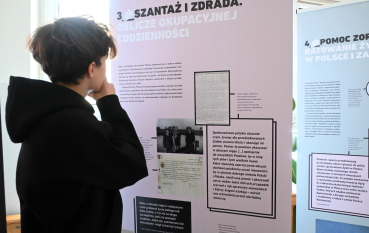 Uczeń ogląda planszę pt. Szantaż i zdrada. Oblicze okupacyjnej codzienności wystawy „W imię człowieczeństwa. Polacy, którzy ratowali Żydów podczas okupacji niemieckiej”