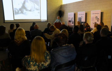 Uczestnicy seminarium słuchają prelekcji z prezentacją multimedialną na ekranie.