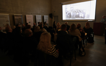 Uczestnicy seminarium słuchają prelekcji z prezentacją multimedialną na ekranie.