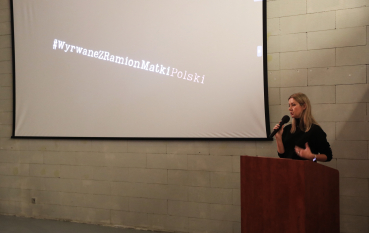 Prelegentka przemawia podczas seminarium, a na ekranie wyświetlony jest slajd prezentacji.