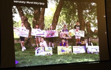 Wyświetlony slajd prezentacji z grupą młodzieży trzymająca plakaty stworzone przez siebie.