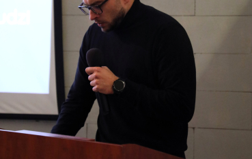 Mężczyzna przemawia przy mównicy.