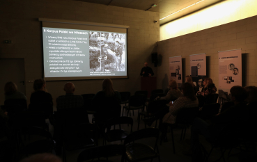 Uczestnicy seminarium słuchają prelekcji z prezentacją multimedialną na ekranie.