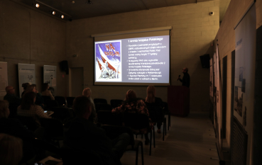 Uczestnicy seminarium słuchają prelekcji z prezentacją multimedialną na ekranie.