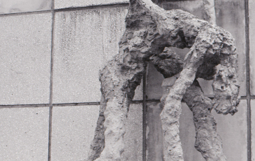 A close-up of an expressive sculpture of two emaciated human figures against the backdrop of the monument’s wall.