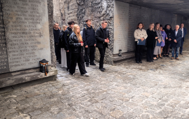 Młodzież i dorośli przechodzą do Niszy Ohel. Na betonowych ścianach wykute są imiona ofiar. Uczniowie niosą zapalone znicze.