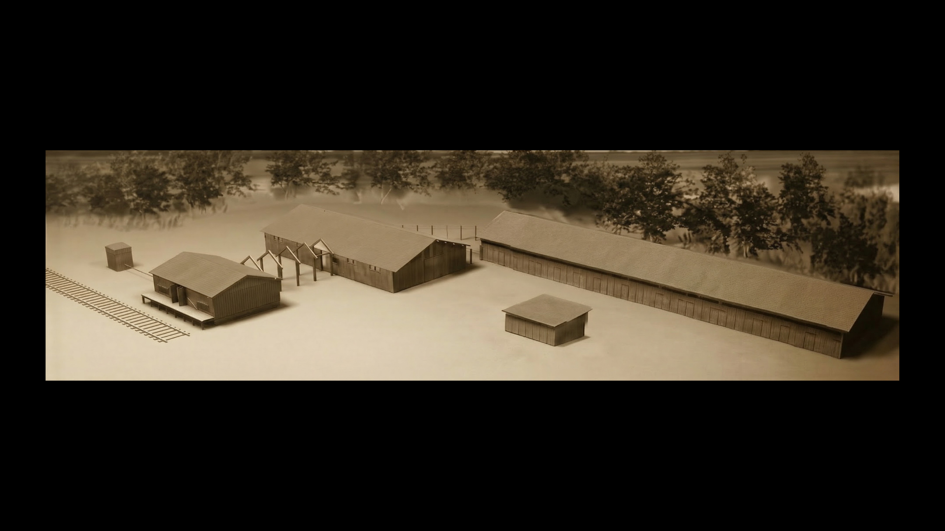 Diorama/model jest rekonstrukcją pierwszych zabudowań obozu zagłady w Bełżcu. Zdjęcie jest utrzymane w sepii. Widoczne są tu budynki obozowe, w tym: tory kolejowe, rampa wyładunkowa, budynek z komorami gazowymi, budynek fryzjeri oraz rozbieralni. Diorama oddaje układ i wygląd pierwszych zabudowań obozu.