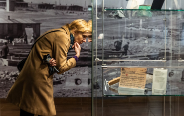 Kobieta stoi przy gablocie z dokumentami. 