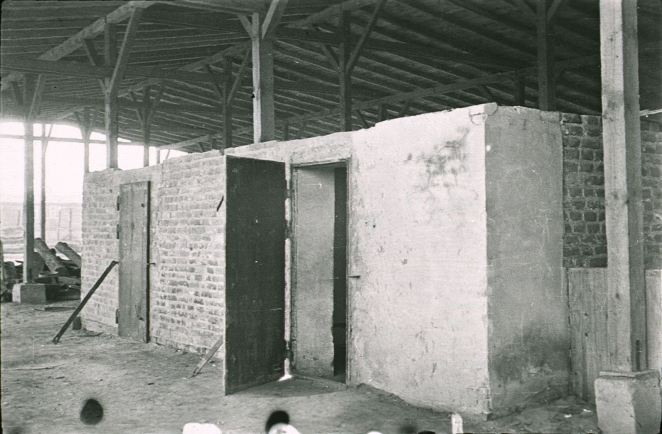 Czarno-białe zdjęcie, betonowa prostokątna zabudowa, dwie pary drzwi, wiata