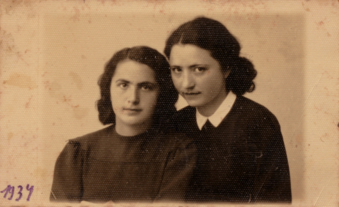 Zdjęcie dwóch młodych kobiet przytulonych do siebie. Mają ciemne włosy do ramion i ciemne sukienki